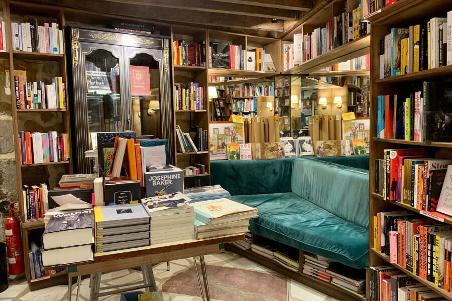 schon lange kein Paris Insider Tipp mehr: der Buchladen Shakespeare & Company Eine gemütliche Buchhandlung mit vielen bunten Büchern, einem samtgrünen Sofa und einem Tisch voller Lesestoff. Die Holzregale und Spiegel verleihen dem Raum ein warmes Ambiente.