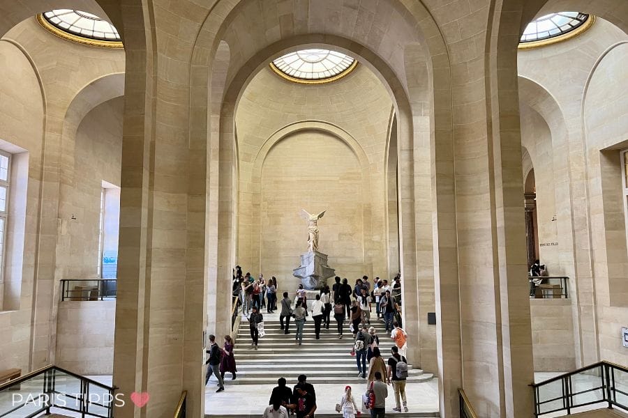 Marmorskulptur der Nike von Samothrake auf einem Schiffsbug im Louvre, umgeben von Besuchern