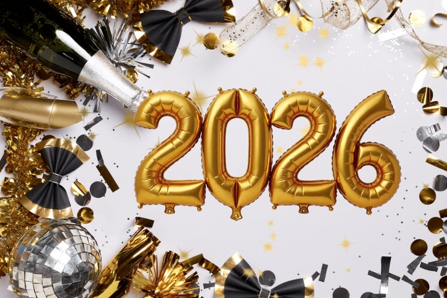 Eine festliche Szene mit goldenen Ballons in Form der Zahl „2026“, umgeben von funkelnder Dekoration. Champagner, eine Diskokugel und schwarze-goldene Bänder sorgen für eine elegante Silvesterstimmung. Das Bild zeigt eine glanzvolle Atmosphäre voller Vorfreude auf das neue Jahr.