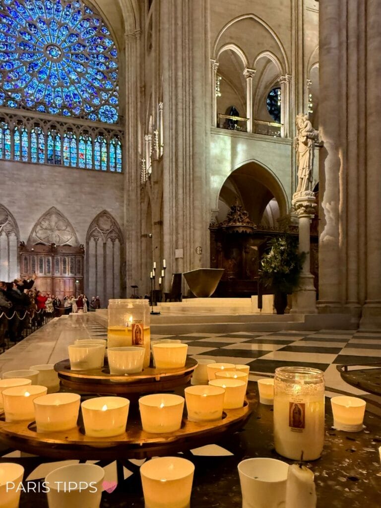 Innenraum der Kathedrale Notre-Dame mit leuchtender Rosette und brennenden Kerzen im Vordergrund – stiller Moment nach der Wiedereröffnung.
