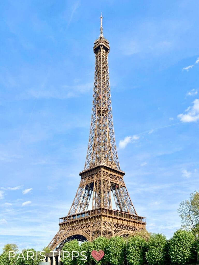 EiffelTurm mit Blauem himmel im hintergrund und grünen Baumen am Fusse