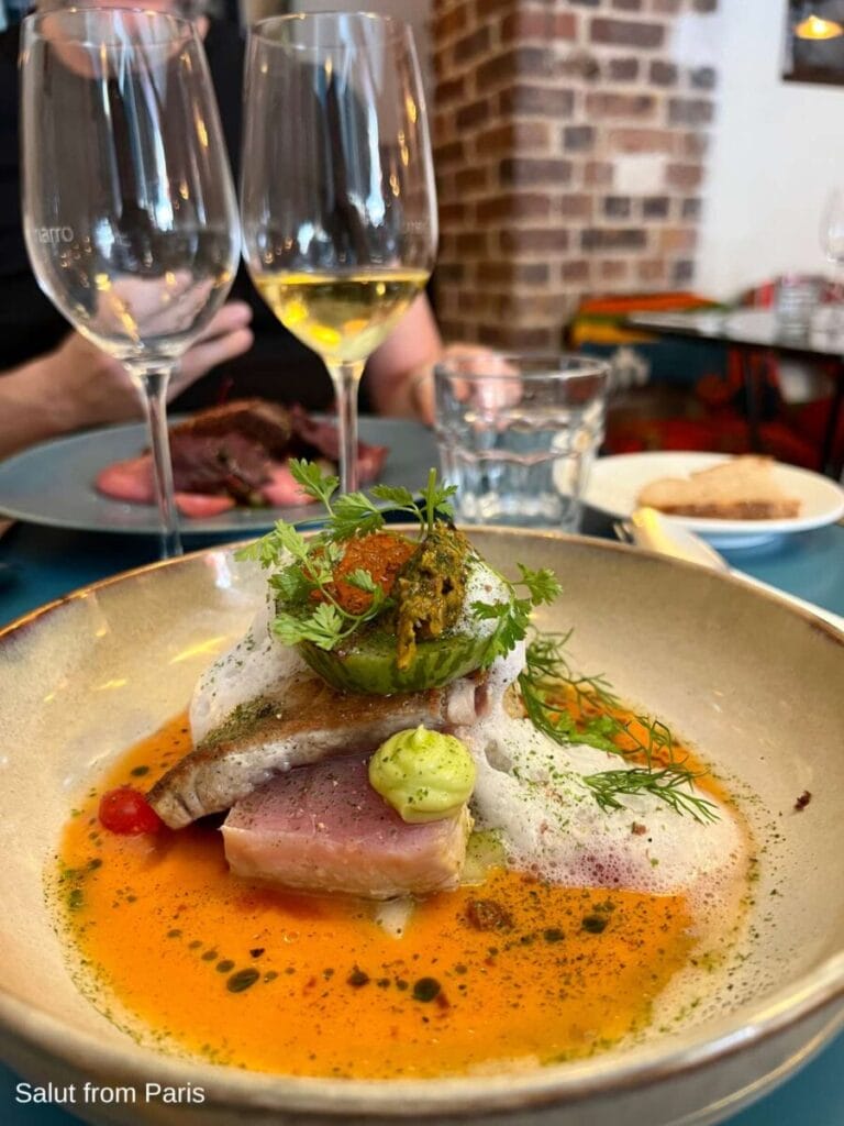 Tunfisch in organfarbener Soße garniert mit grünem Gemüse im Pariser Restaurant