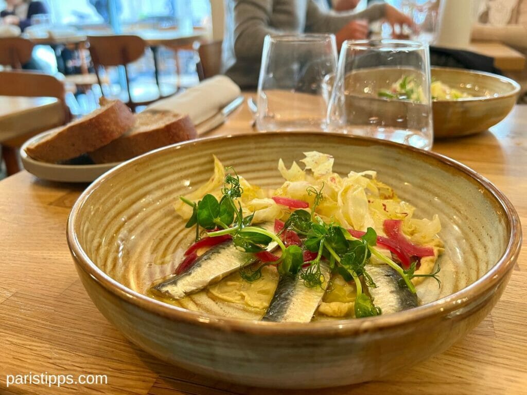 Teller mit Salat, Humus und Sardinen