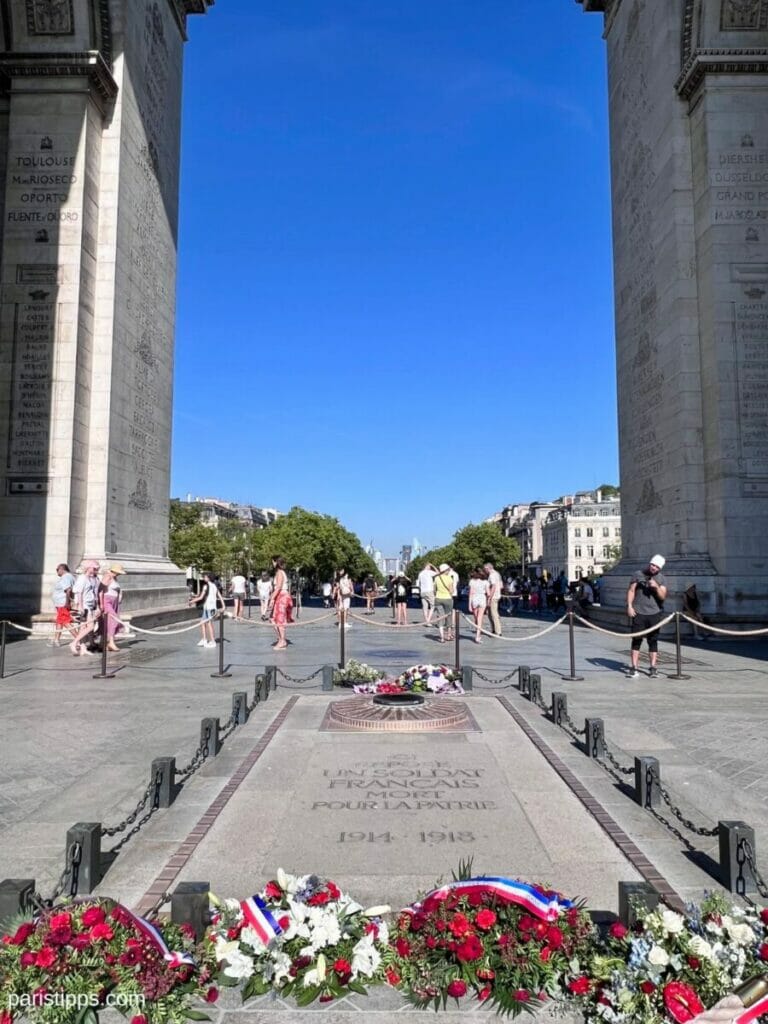 Grab des Unbekannten Soldaten mit ewiger Flamme unter dem Triumphbogen in Paris, geschmückt mit Blumen und Kränzen.