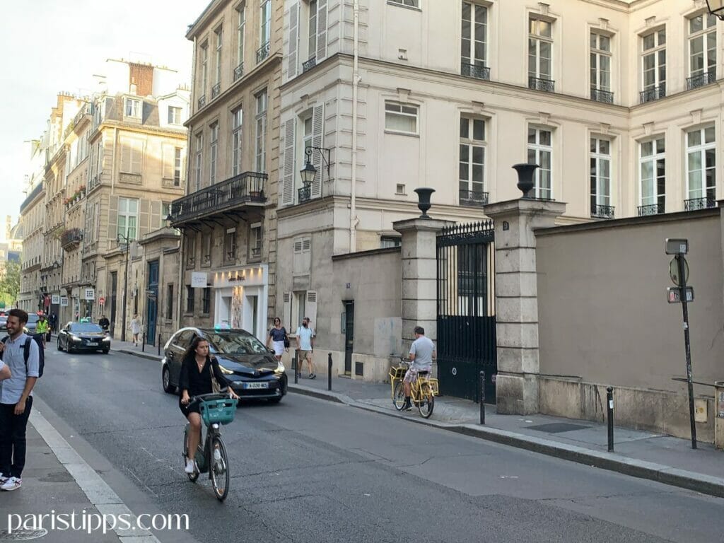Radfahrer im Straßenverkehr in Paris auf einer typischen Stadtstraße ohne separaten Radweg. Die Szene zeigt, wie das Fahrradfahren in Paris oft direkt im Verkehr stattfindet und Aufmerksamkeit erfordert. Besonders für Anfänger kann das ungewohnt sein.
