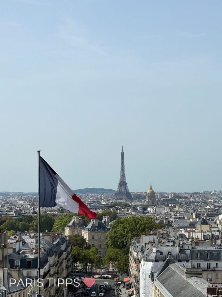 Blick über die Dächer von Paris mit einer französischen Flagge im Vordergrund sowie Eiffelturm und goldener Kuppel von Les Invalides in der Ferne. Der Schriftzug "PARIS TIPPS ♥" unterstreicht diese Panorama Paris Sehenswürdigkeiten Aussicht.