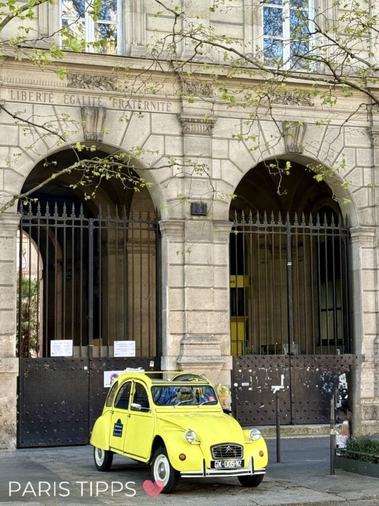 Gelbe Ente steht vor einem historischen Gebäude mit Bögen und der Inschrift „LIBERTÉ ÉGALITÉ FRATERNITÉ“ in Paris. „PARIS TIPPS ❤️“ steht unten im Bild und zeigt eine charmante Szene einer Stadtrundfahrt Paris.