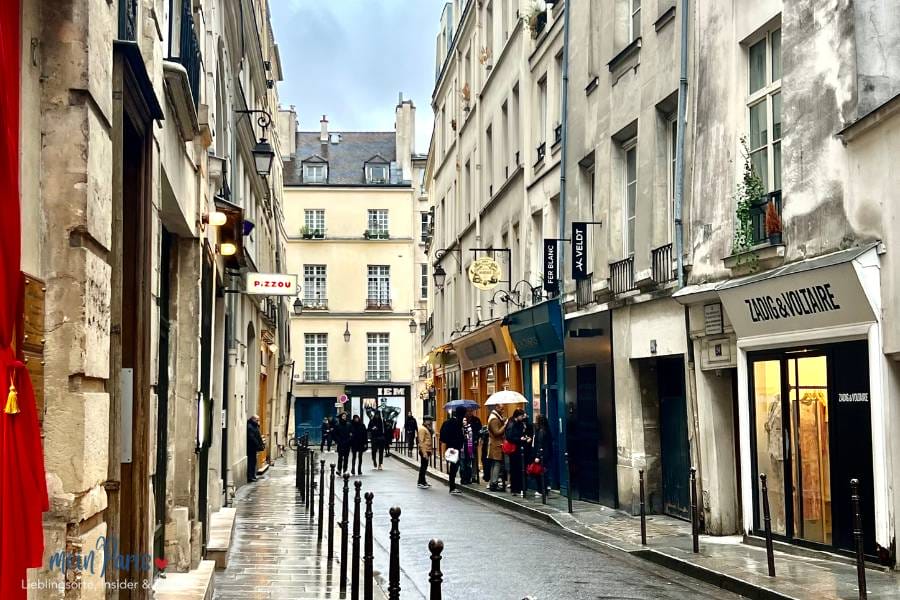 Marais in Paris Sonntag Shoppen, regennasse Strasse mit Häusern links und rechts. Altbau mit grauen Fassaden