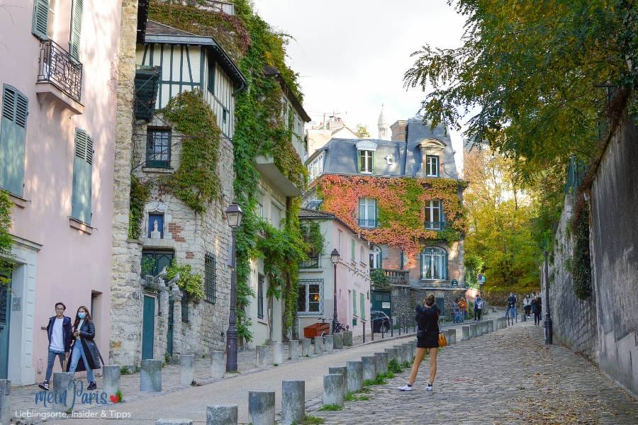 Montmartre Kopfsteinpflaster Strasse und efeu bewachsene Häuser im Hintergrund. Herbstliche Stimmung mit orangenen Bläggern. 