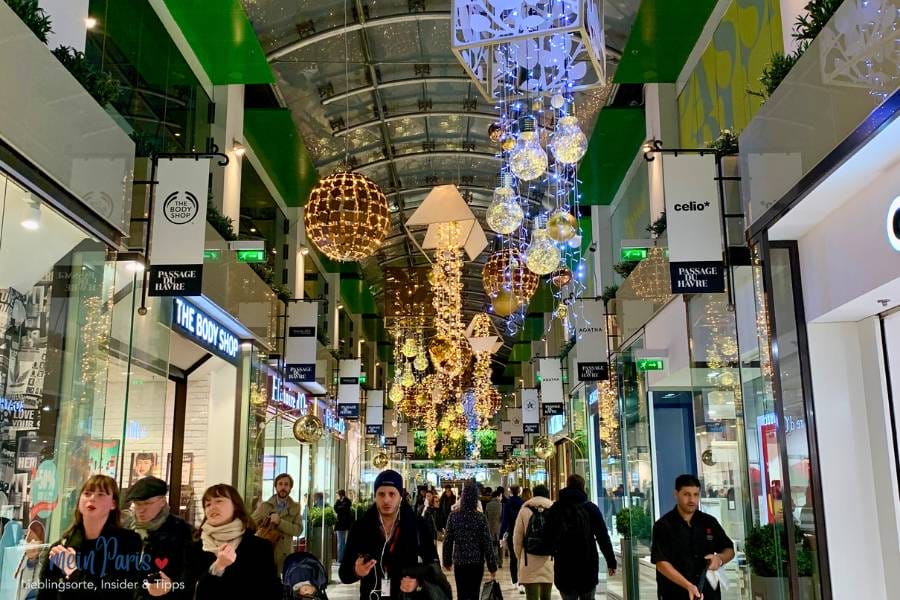 Passage mit grünlicher Weihnachtlicher Deko und vielen Menschen im Vordergrund