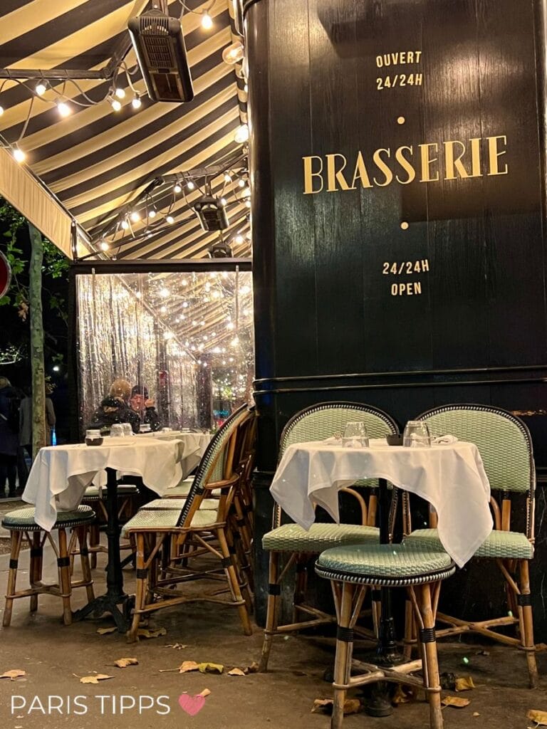 Gemütliche Pariser Brasserie mit gedeckten Tischen und stilvollen Bistrostühlen, beleuchtet von warmen Lichterketten, einladend für eine Nacht in der Stadt.